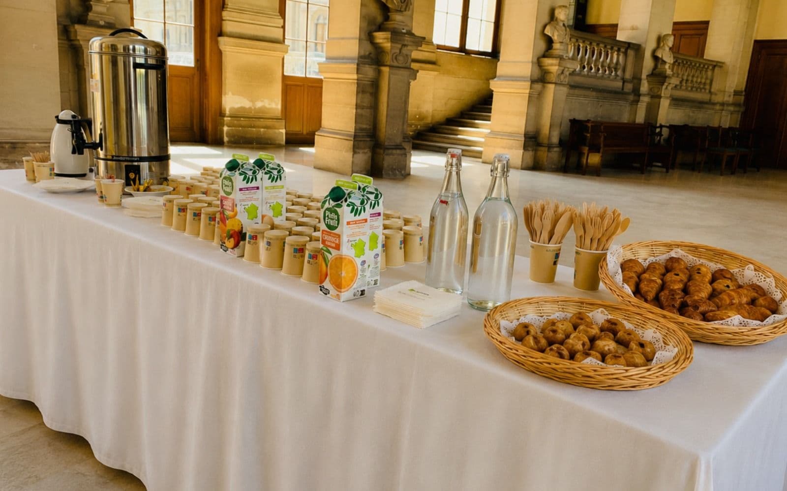 Pause café SOUBISE — thermos, croissants et jus dans une salle de réception classique